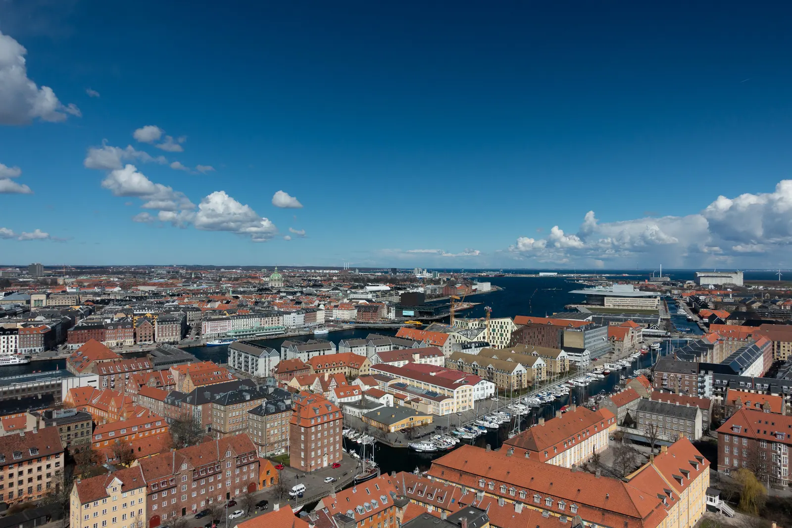 A wide view over red-roofed city blocks toward the water.