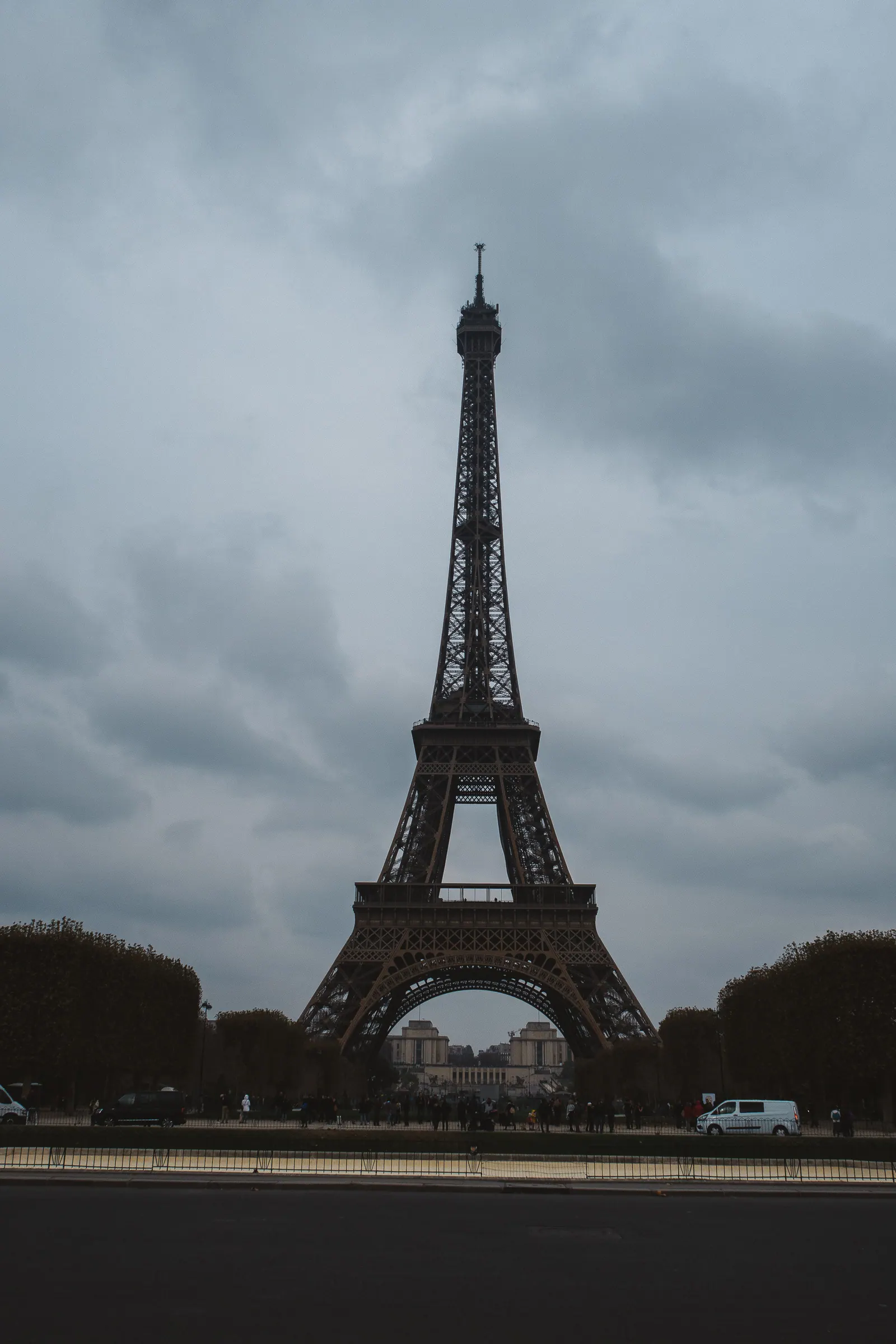 The iron tower rising above trees under a grey sky.