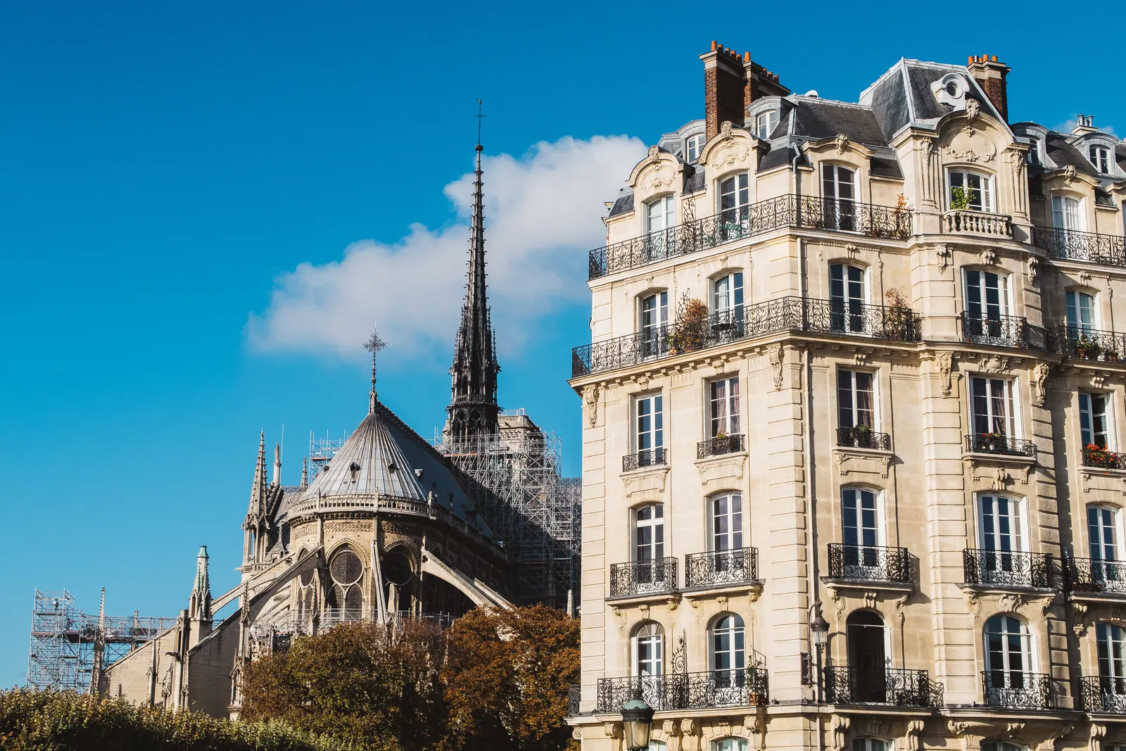 A cathedral spire beside ornate Haussmann apartment buildings.