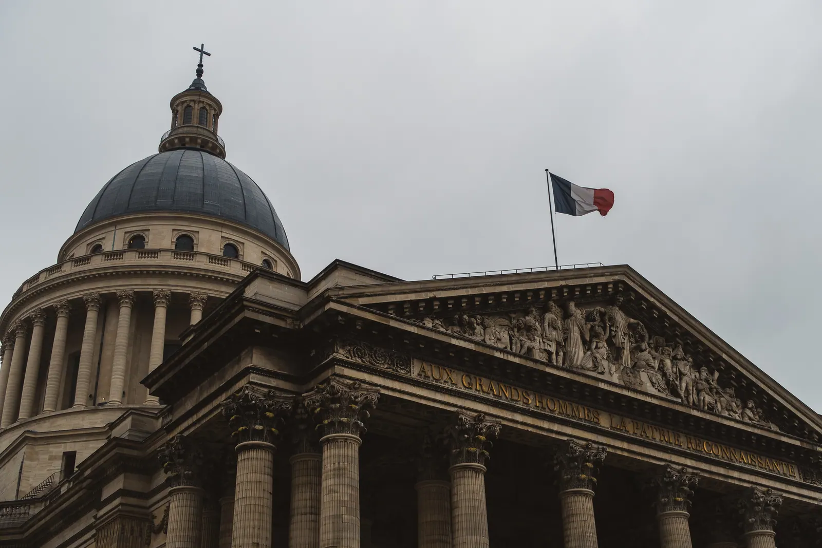 A domed neoclassical facade with a French flag flying.