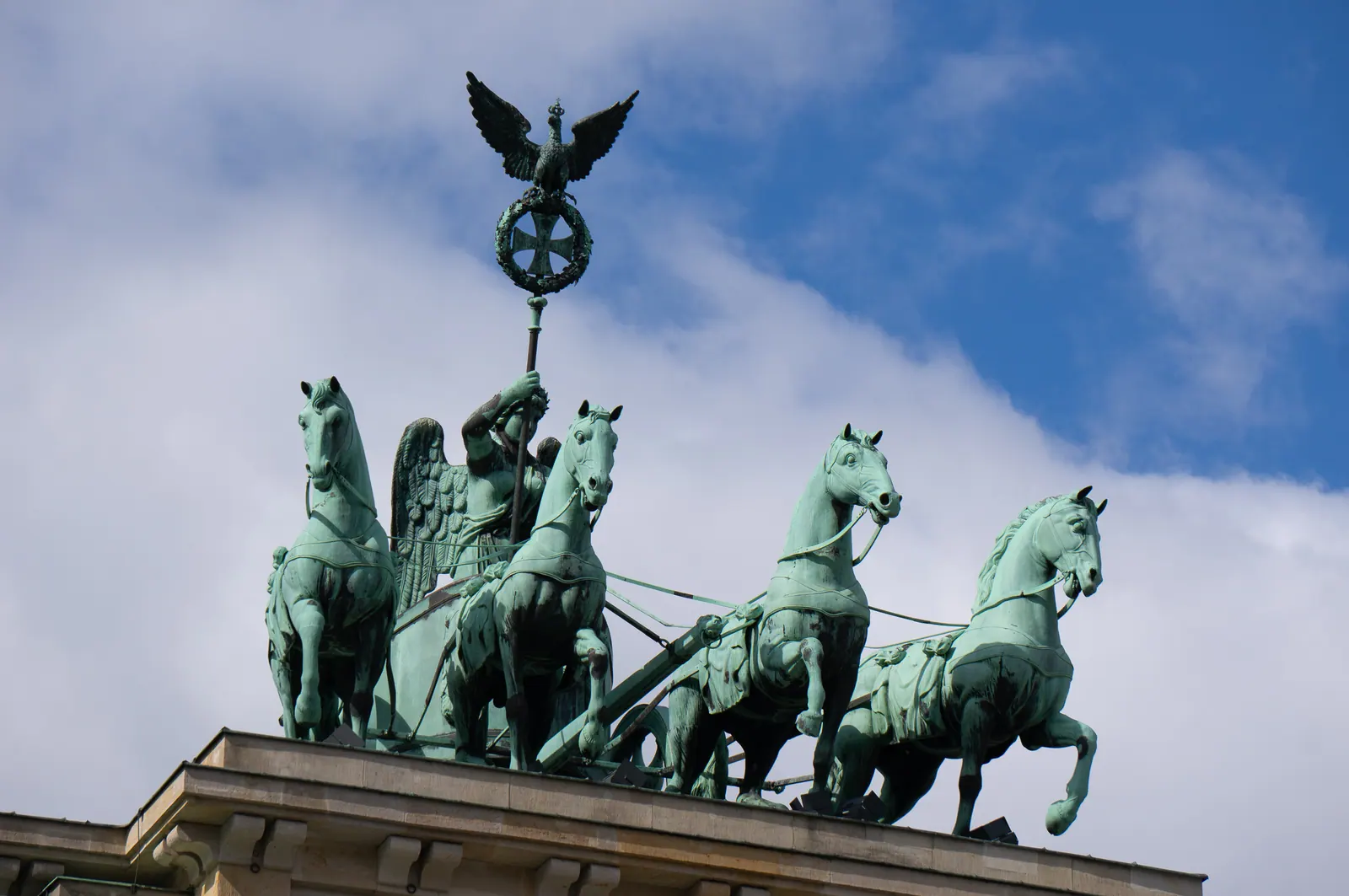 The bronze chariot and horses atop a gate against a cloudy sky.