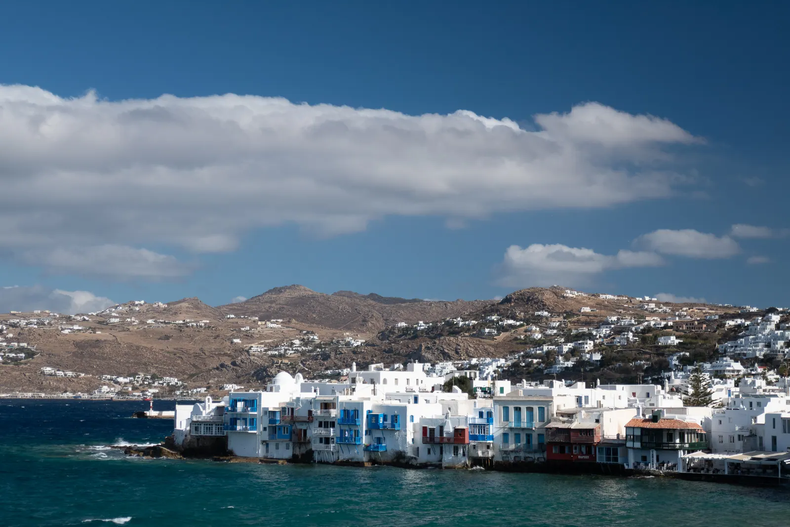 Whitewashed houses right at the water's edge beneath a wide sky.