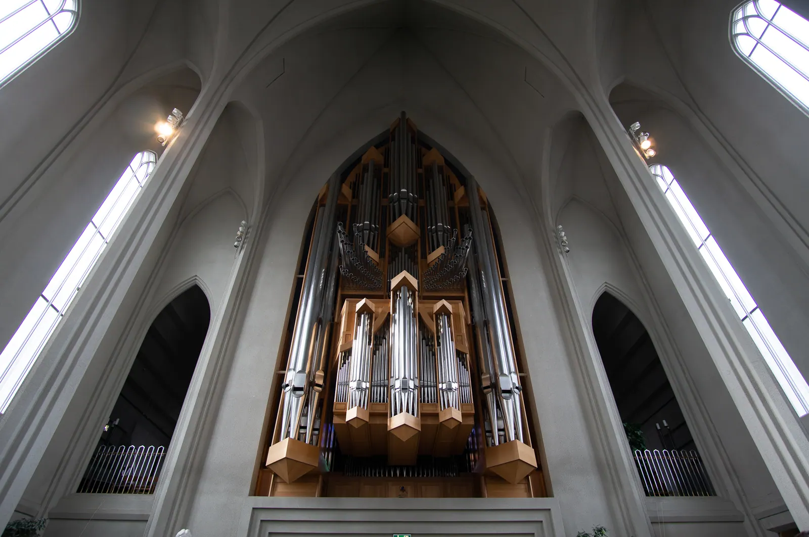 Looking up the white concrete nave of a church toward its pipe organ.
