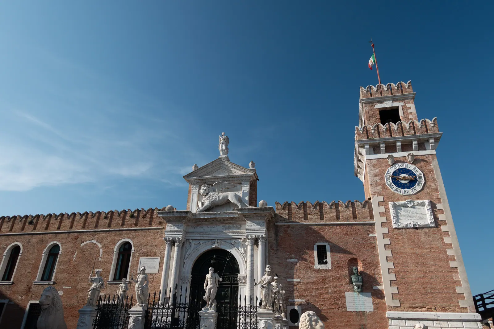 A crenellated brick gate tower under a clear blue sky.