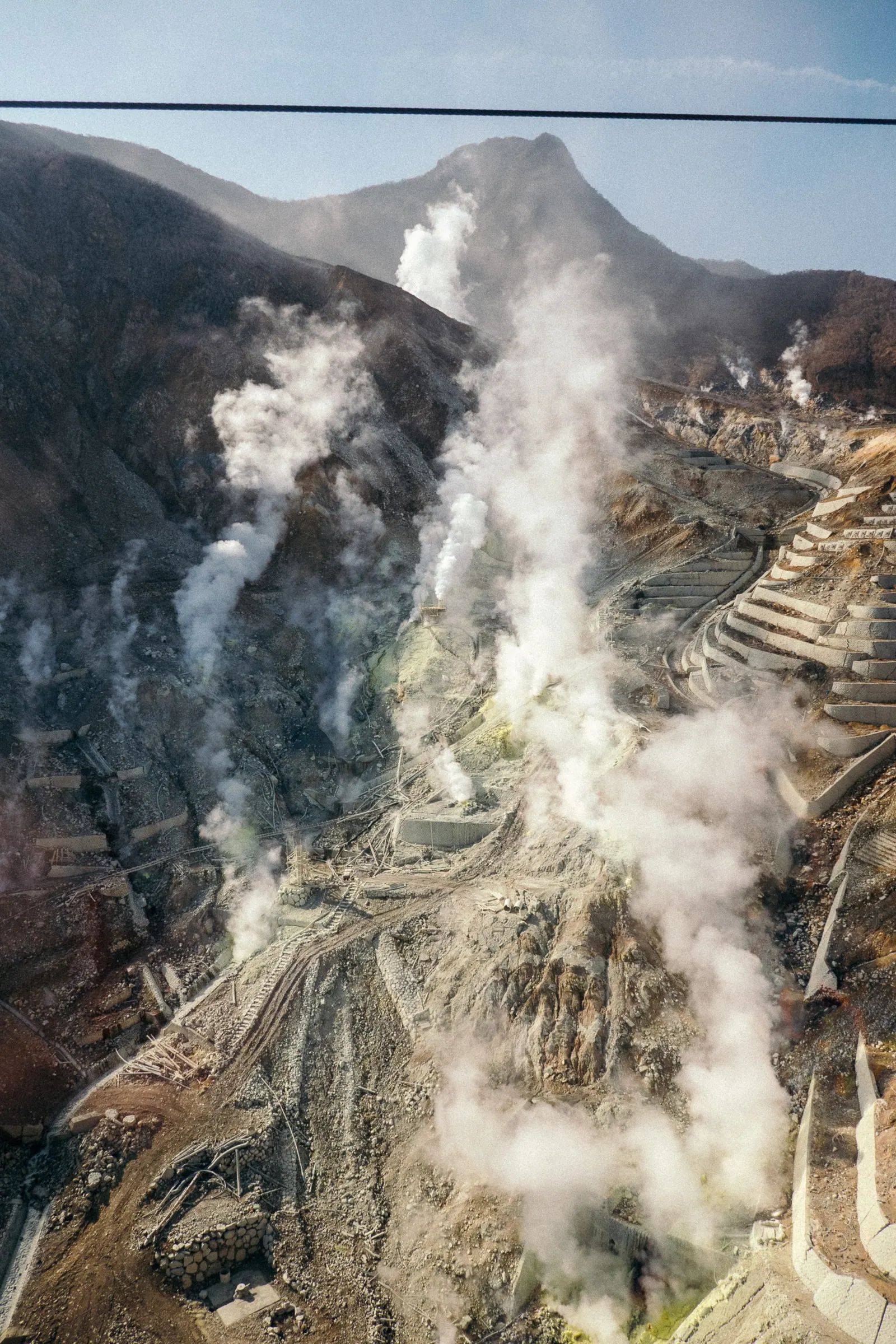 Volcanic steam rising from a barren mountainside.