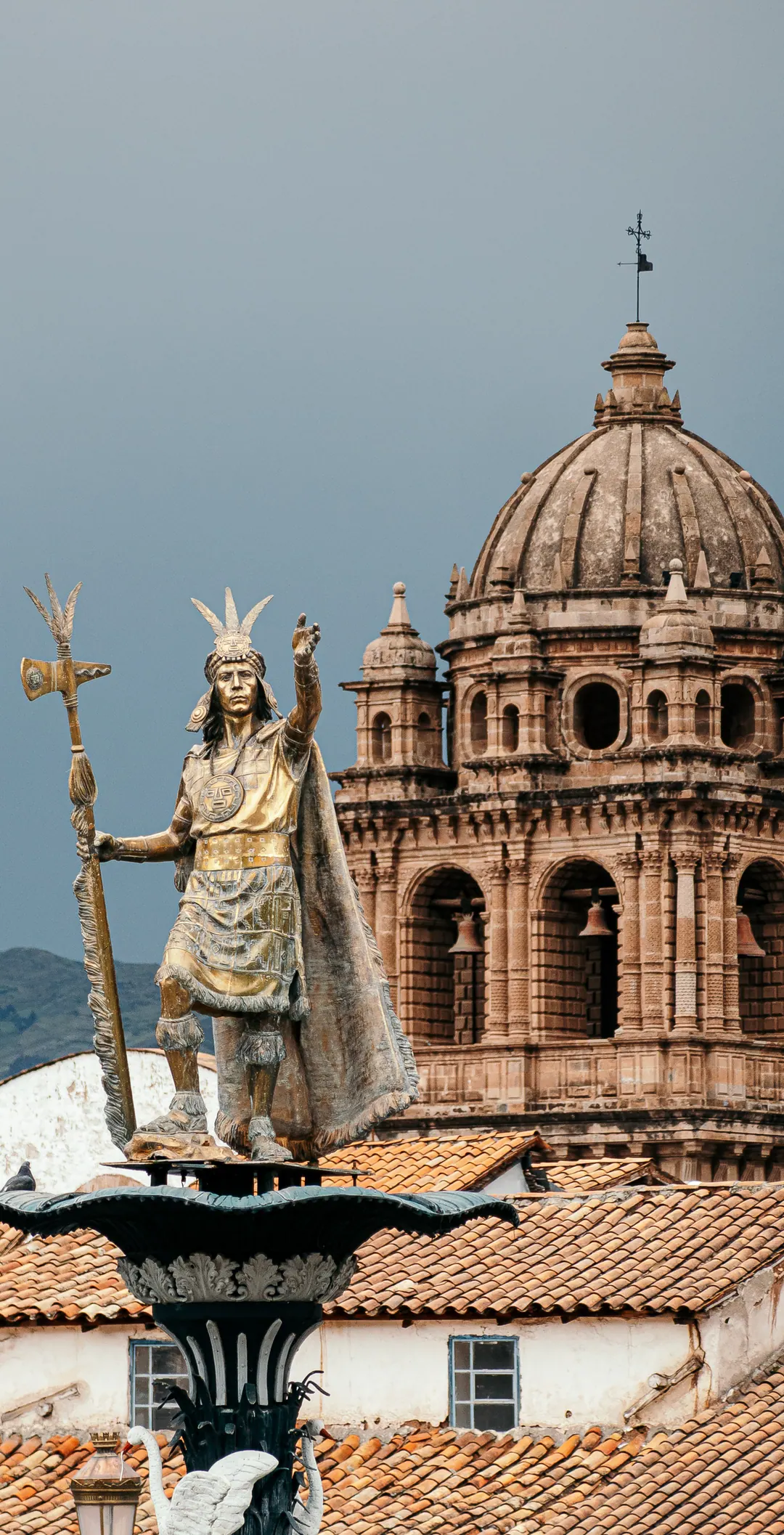 A statue on a fountain in front of a domed church tower.