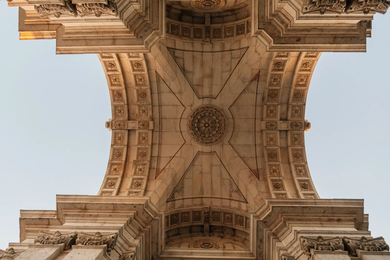 Looking straight up into the carved vault of a triumphal arch.
