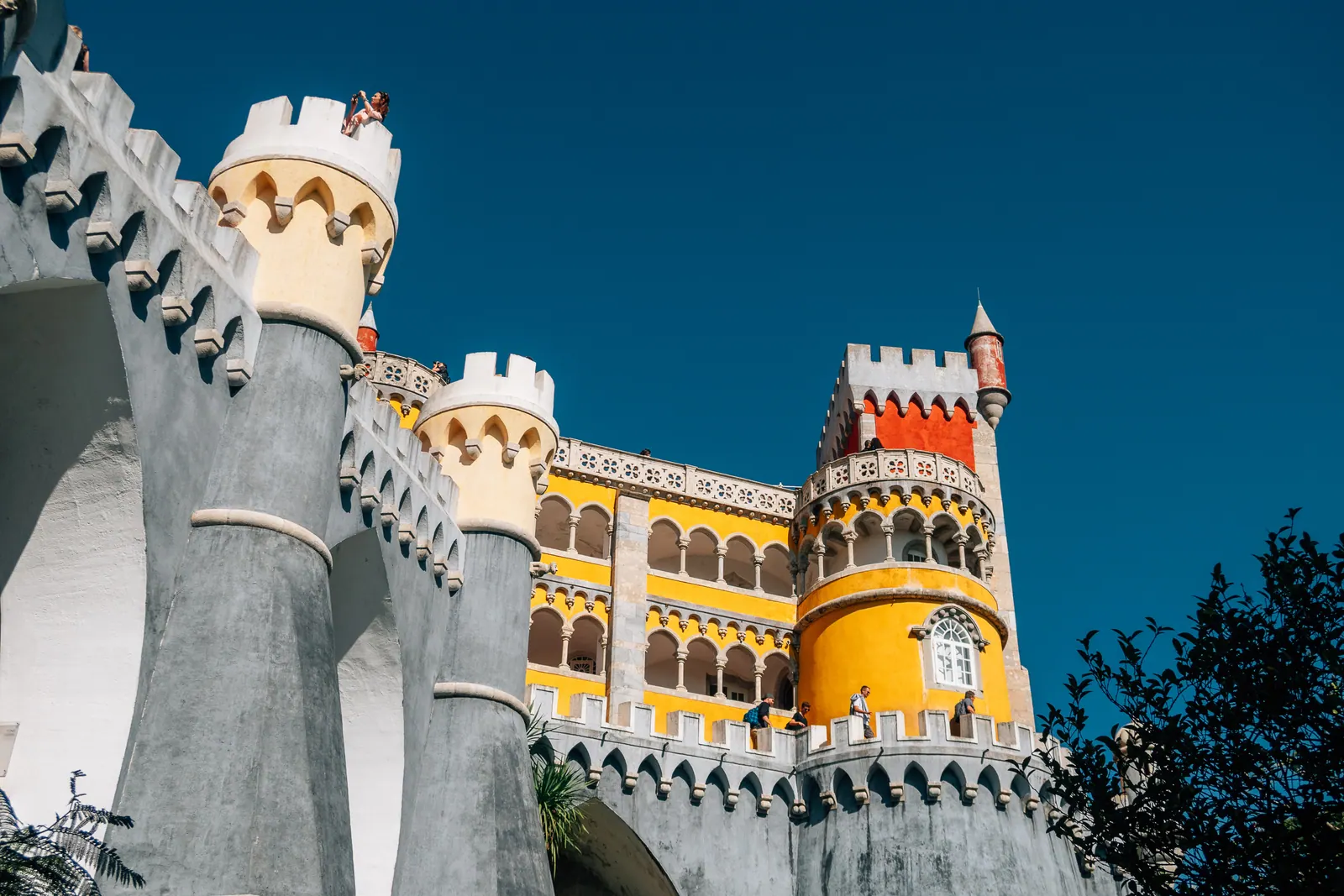 Crenellated towers of a palace painted grey and yellow.