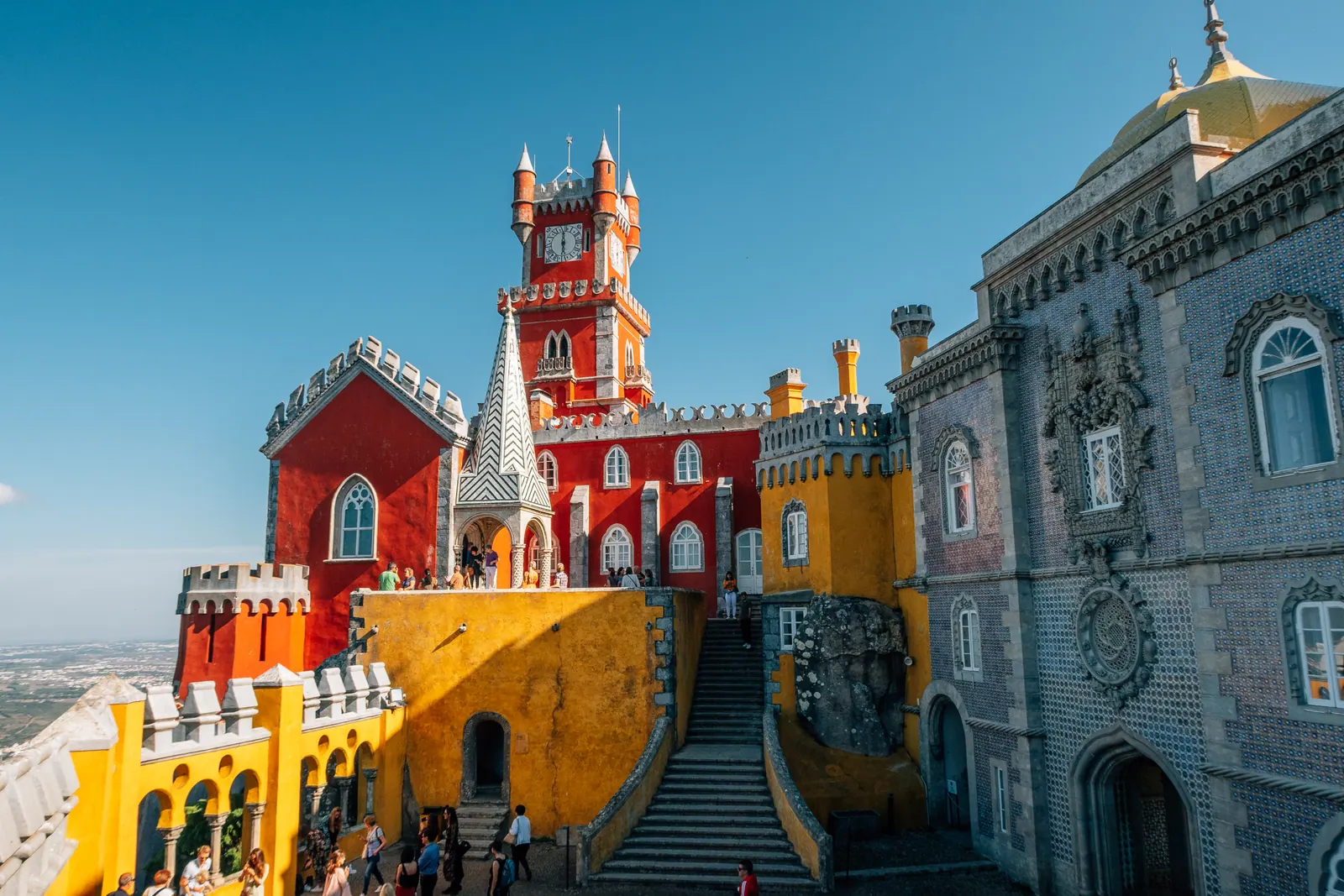 Red and yellow palace walls and towers around a courtyard.